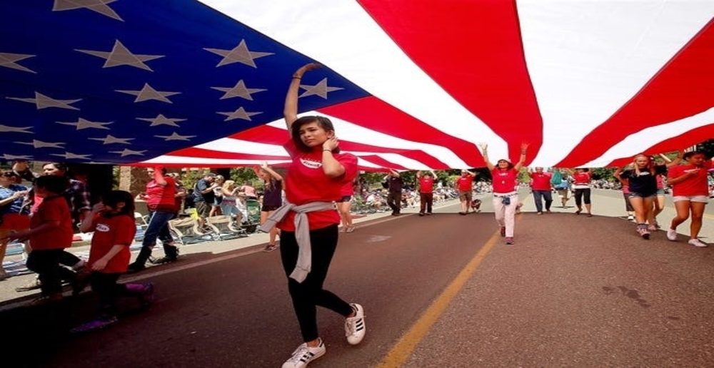 People walking and holding up one large American flag.